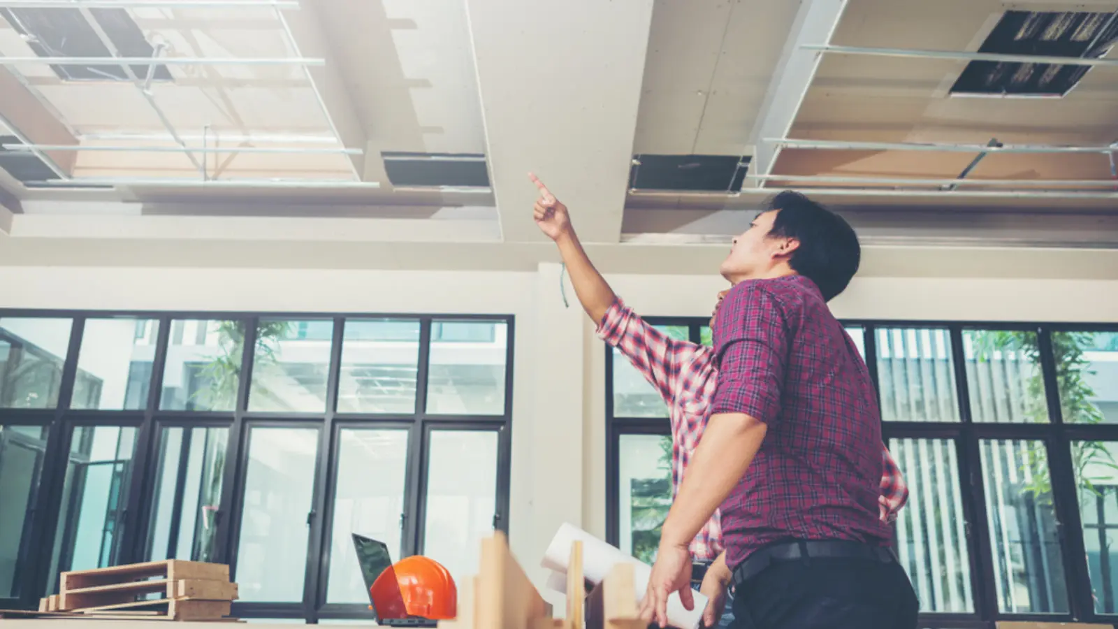 Engineer inspecting ceiling voids, MEP services or raised access flooring during a building survey.