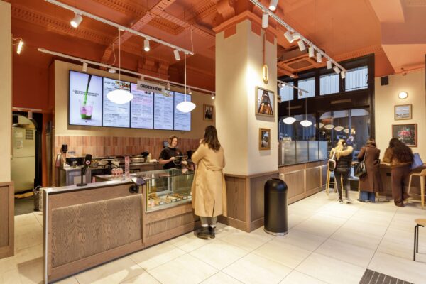 Interior of Joe & The Juice High Holborn showing the order counter, a retained column and window seating under decorative cornicing.