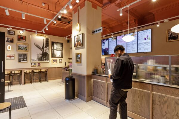 Bar seating and a framed gallery wall beside the collection counter at Joe & The Juice High Holborn.