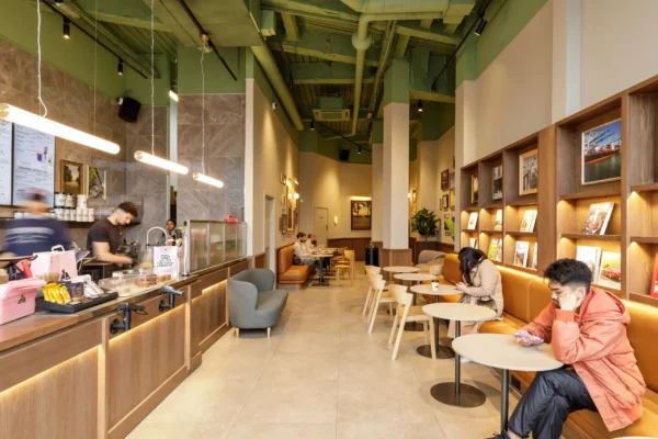 Long servery counter and banquette seating at Joe & The Juice Wimbledon under a green painted exposed ceiling