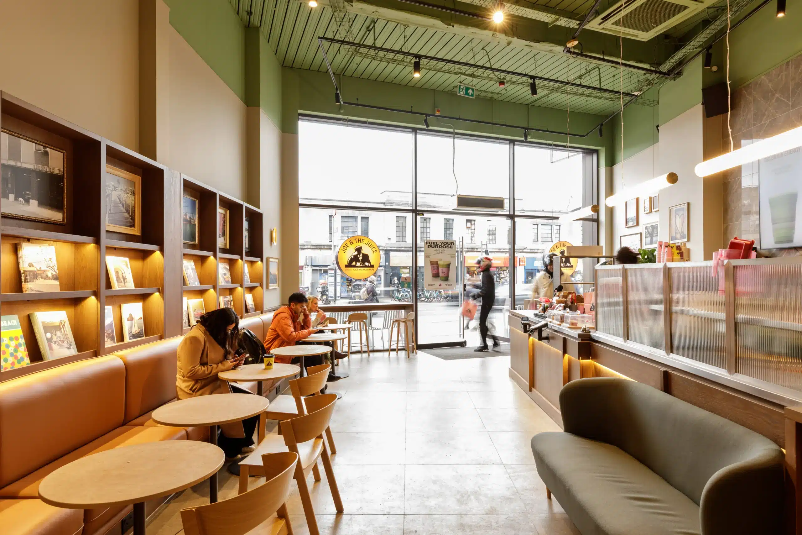 Interior of Joe & The Juice Wimbledon looking towards the glazed shopfront, with banquette seating, display shelving and servery