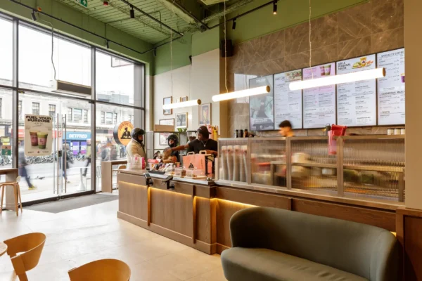 Joe & The Juice Wimbledon servery counter with timber front and LED underlighting beside the glazed entrance